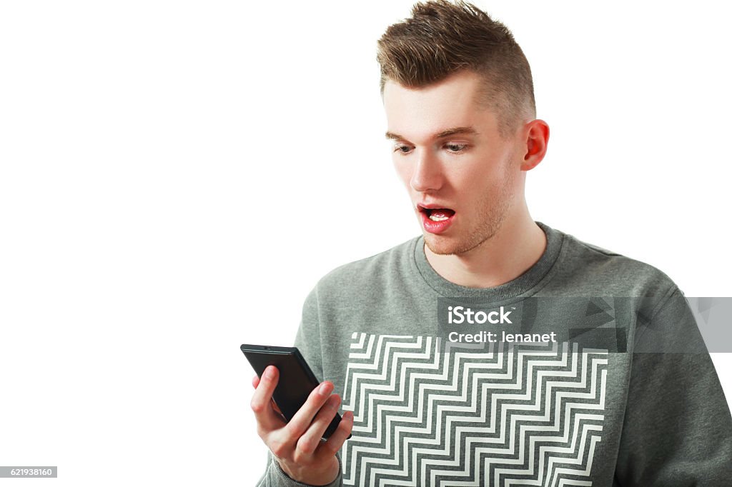 amazed young man using smartphone Shocked news! Studio portrait of amazed young man using smartphone. Isolated on white. 20-29 Years Stock Photo