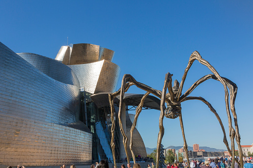 Bilbao, Spain - October 29, 2016; Back of the Guggenheim Museum, contemporary art, work of the Canadian architect Frank O. Gehry, and the sculpture of the spider of Louise Bourgeois. There  are people walking 