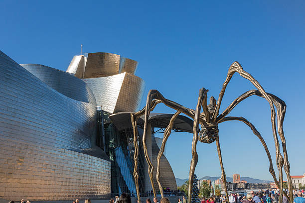 Guggenheim Museum Bilbao, Spain - October 29, 2016; Back of the Guggenheim Museum, contemporary art, work of the Canadian architect Frank O. Gehry, and the sculpture of the spider of Louise Bourgeois. There  are people walking  frank gehry building stock pictures, royalty-free photos & images