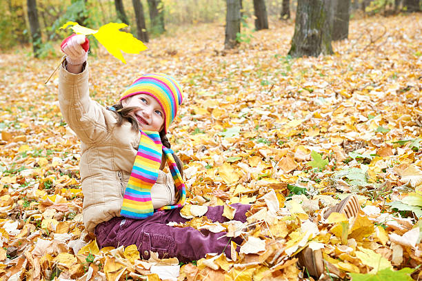istock girl child in autumn forest, sit on leaves 621973308