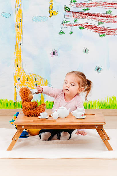 お茶会で彼女のテディベアと遊ぶ小さな女の子 - tea party little girls teapot child ストックフォトと画像