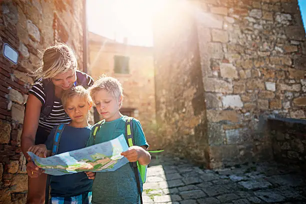 Photo of Mother and tourist sons checking map in an Italian town