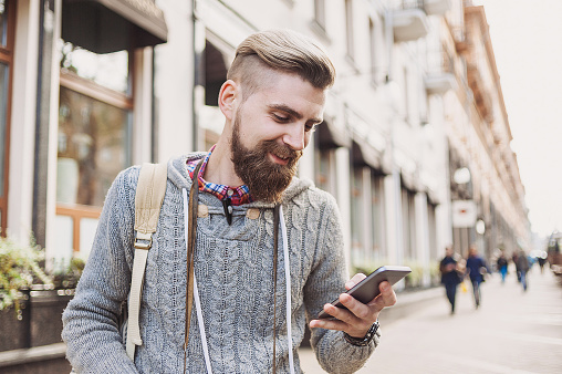 Young man texting on his smart phone outdoors