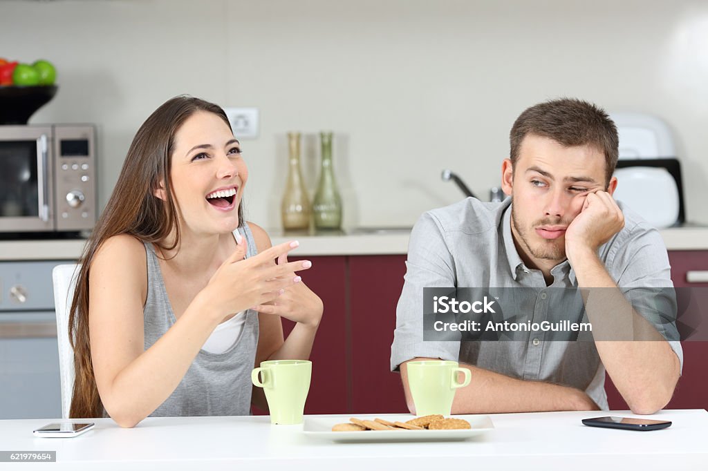 Bored husband hearing his wife talking Bored husband hearing his wife talking during breakfast in the kitchen at home Boredom Stock Photo