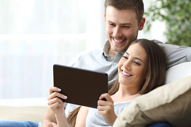 pareja viendo medios en una tableta - apartment television family couple fotografías e imágenes de stock