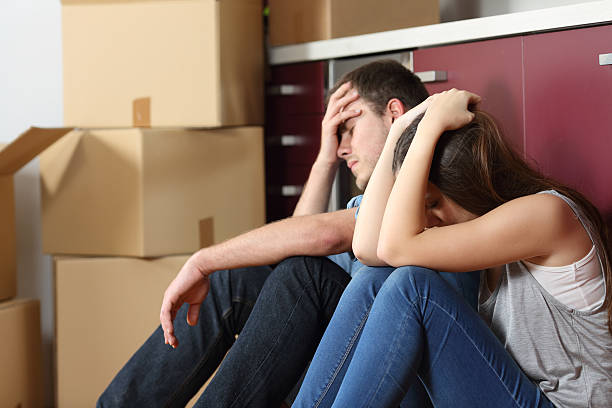 Sad evicted couple worried moving house Angry evicted couple worried moving house sitting on the floor in the kitchen eviction photos stock pictures, royalty-free photos & images