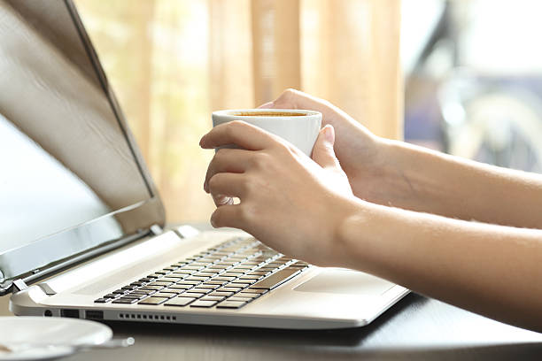 istock Girl hands with coffee watching laptop 621980622