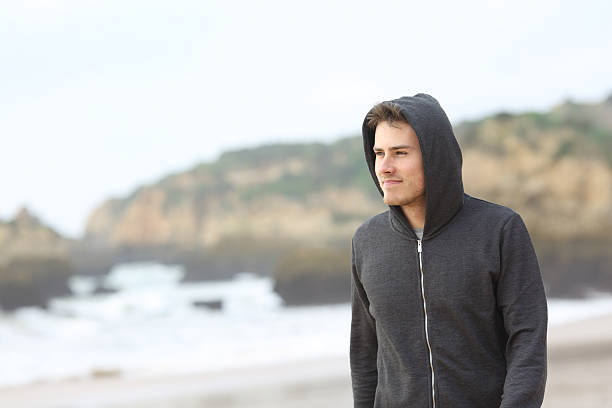 Portrait of a confident teenager walking on the beach in a rainy day
