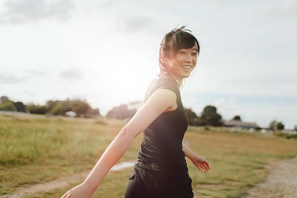 femme coureuse marchant sur le terrain le matin - running jogging asian ethnicity women photos et images de collection