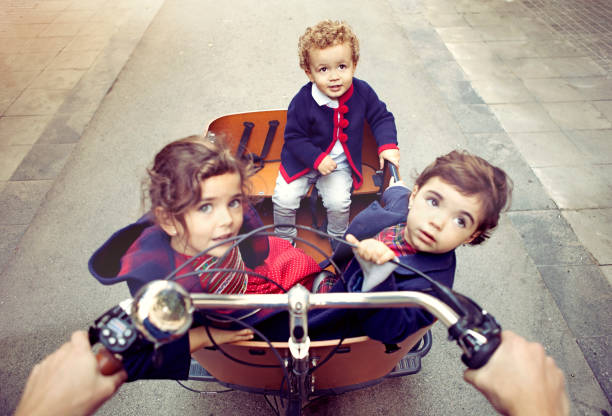 padre montando bicicleta de carga - familia con tres hijos fotografías e imágenes de stock