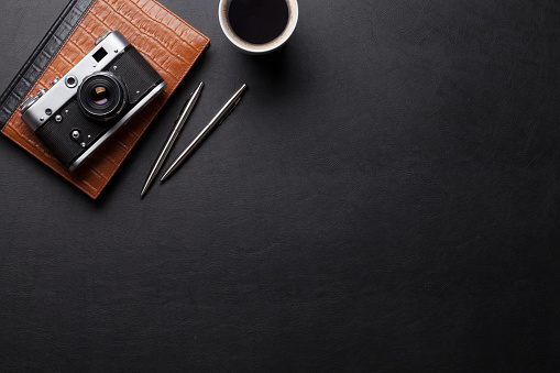 Office desk with photo camera, coffee and notepad. Top view with copy space