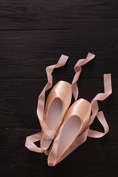 istock Pink ballet pointe shoes on black wood background 621995508