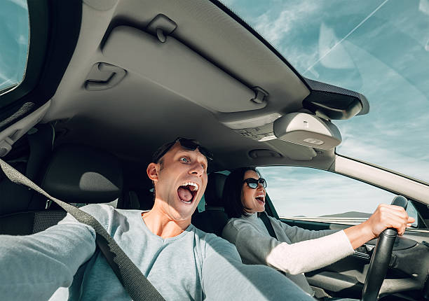 istock Screaming couple riding in car wide angle view 621996184