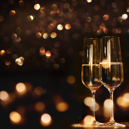 Champagne glasses for a new year against a dark background with gold shimmering light