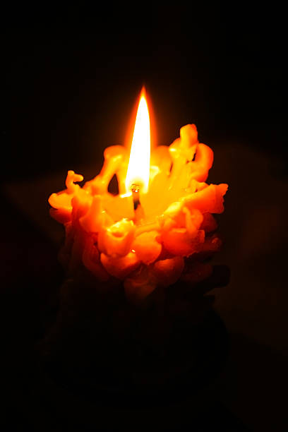 istock Burning candle in shape of pine cones on black background. 621997366