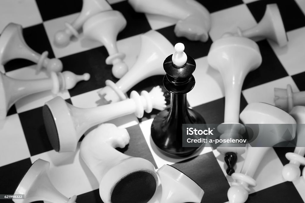 Rei do xadrez negro entre inimigos derrotados. Vitória total - Foto de stock de Branco royalty-free Rei do xadrez negro entre inimigos derrotados. Vitória total - Foto de stock de Branco royalty-free