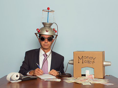 A businessman sitting at a desk records the amount of British Pound Sterling his machine makes from the ideas in his head.  He is dressed in a suit and purple tie, glasses, and a mind reading helmet on his head. Bling.