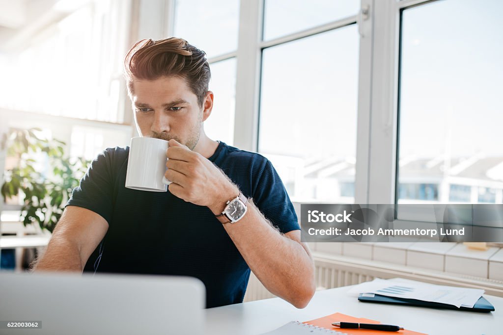 Geschäftsmann trinkt Kaffee und arbeitet am Laptop im Büro - Lizenzfrei Kaffee - Getränk Stock-Foto