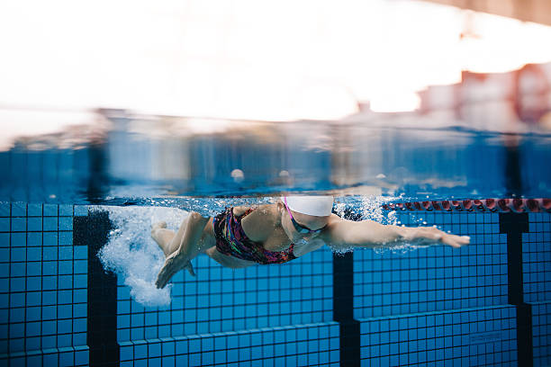 Female swimmer training in the swimming pool Underwater shot of female swimmer swimming in pool. Fit young female swimmer training in the pool. women exercising swimming pool young women stock pictures, royalty-free photos & images