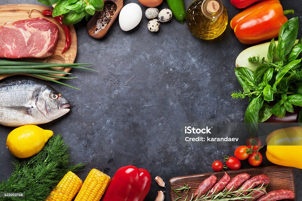 Vegetables, fish and meat cooking Vegetables, fish, meat and ingredients cooking. Tomatoes, eggplants, corn, beef, eggs. Top view with copy space on stone table Meat Stock Photo