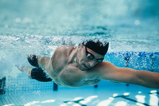 Fit swimmer training in the pool Underwater shot of fit swimmer training in the pool. Professional male swimmer inside swimming pool. sportsperson stock pictures, royalty-free photos & images