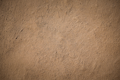 closeup detail of old brown stucco clay wall, rough surface background or backdrop in architectural material concept