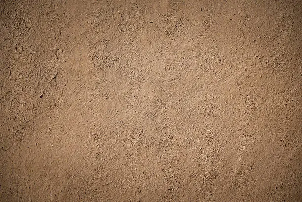 closeup detail of old brown stucco clay wall, rough surface background or backdrop in architectural material concept