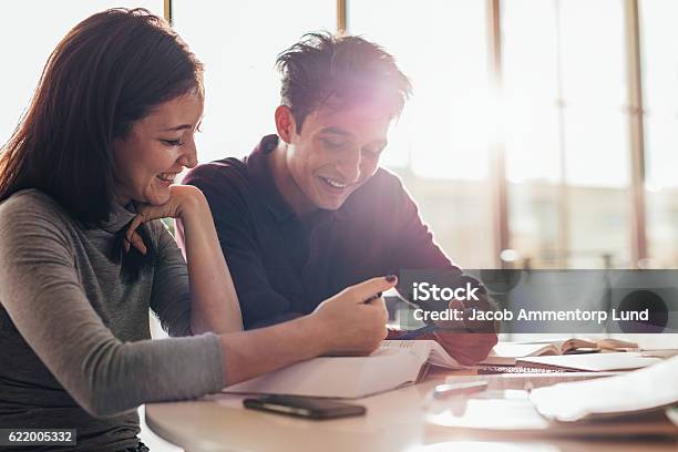 Happy Young Students Reading A Book Together Stock Photo - Download Image Now - Learning, Studying, Advice