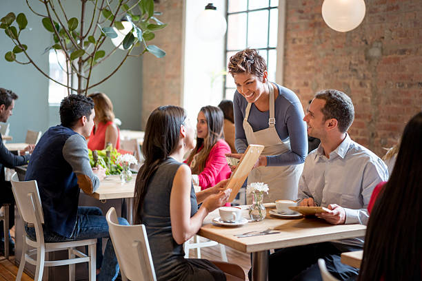 レストランでカップルにサービスを提供するフレンドリーなウェイトレス - restaurant dinner waitress dining ストックフォトと画像