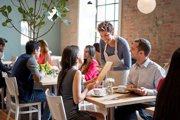 Photo of Friendly waitress serving couple at a restaurant