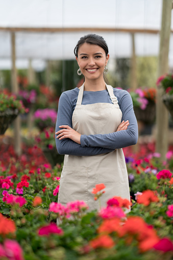 Happy business owner working at a greenhouse and looking at the camera smiling