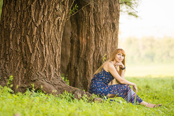 istock Beautiful young woman sat on roots of old large tree 622011734