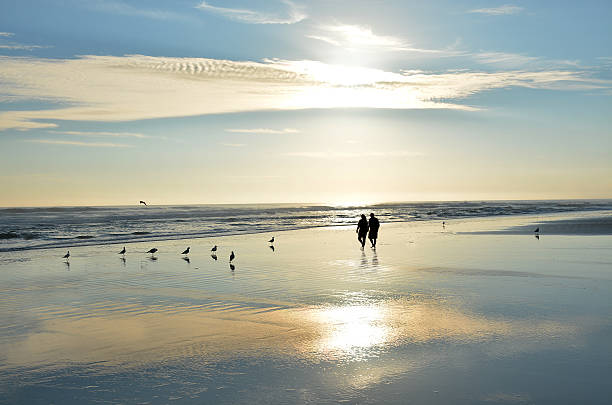 istock Senior couple holding hands walking on beach enjoying sunrise. 622014000