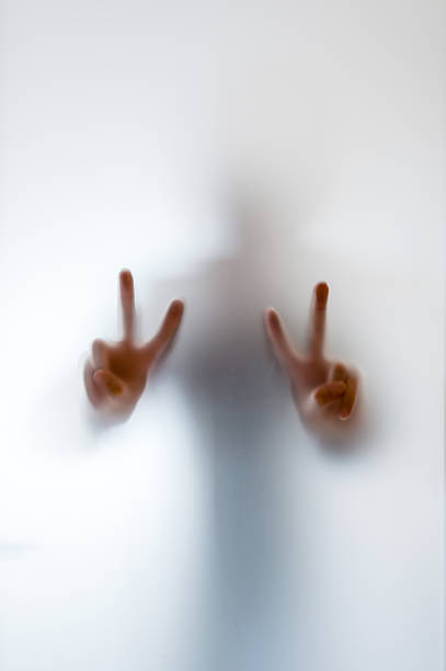 istock Blurry figure of a man making peace sign behind glass 622015092