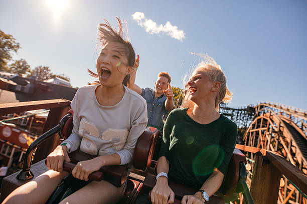 young friends on thrilling roller coaster ride - lunapark treni stok fotoğraflar ve resimler