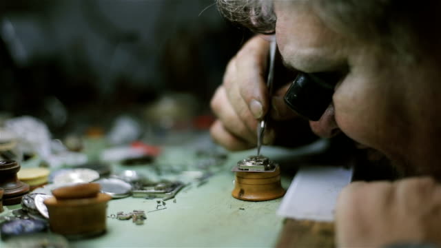 The watchmaker is repairing and maintaining an automatic mechanical watch - fixing and examining pendulum