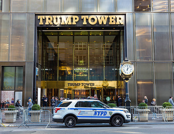 Trump Tower Guarded by NYC Police, 5th Avenue, Manhattan, NY. New York, NY, USA - November 2, 2016: The main entrance of the Trump Tower guarded by NYC Police, Manhattan, New York City. Trump Tower is a 58-story skyscraper located on Fifth Avenue in Midtown Manhattan. The tower is the residence of Donald Trump and family, headquarters of the 2016 Donald Trump presidential campaign and Offices of Donald Trump. Police officers, parked police car, fence, doorman and passersby are in the image. door attendant photos stock pictures, royalty-free photos & images