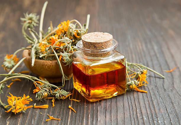 Calendula oil Calendula oil bottle with dried flowers field marigold stock pictures, royalty-free photos & images