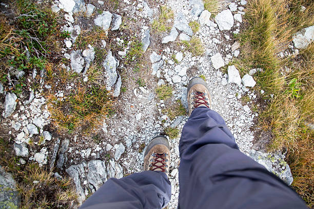 Hiking.Woman legs with hiking boots on the mountain path , top view