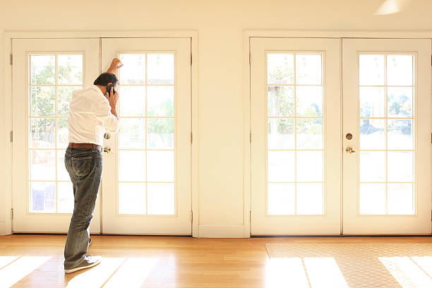 istock Hispanic Looking Out French Doors Talking On Cell Phone 622034480