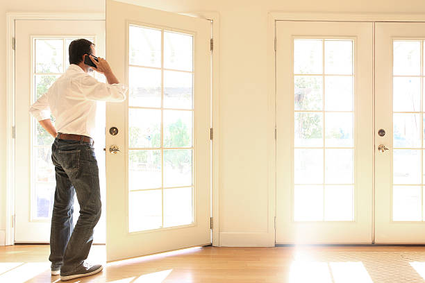 istock Hispanic Man Looking Out French Doors Talking On Cell Phone 622039840