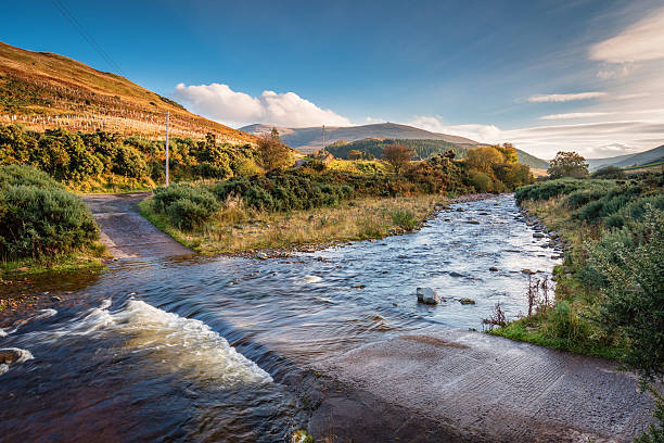Ford on College Burn and The Cheviot The Cheviot, from which the hill range takes its name, is the highest point in Northumberland, located in the Anglo-Scottish borders, seen here in autumn from College Valley northumberland stock pictures, royalty-free photos & images