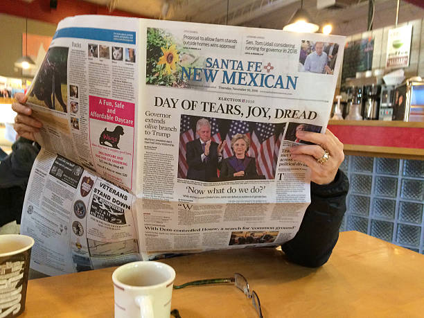 Woman Reads Newspaper with Headline: "Day of Tears, Joy, Dread" Santa Fe, NM, USA - November 10, 2016:  A woman at Downtown Subscription, a local coffee bar, sits at a table reading the Santa Fe New Mexican newspaper with the headline "Day of Tears, Joy, Dread." An accompanying photo shows Hillary Clinton with her husband during her concession speech. hillary clinton stock pictures, royalty-free photos & images