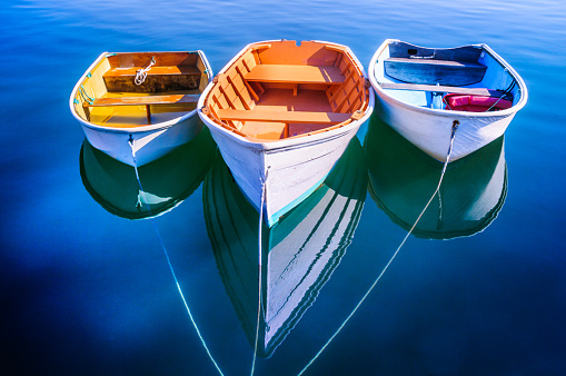 Three rowboats float gently on the quiet waters od Quissett Harboe in Falmouth, Massachusetts on a Autumn afternoon.