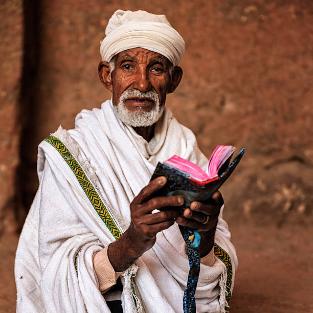 sacerdote de la iglesia tallada en la roca leyendo el libro sagrado, lalibela - rock hewn church fotografías e imágenes de stock