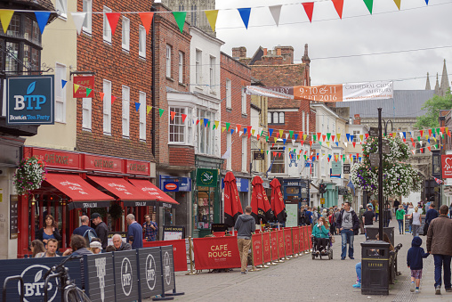 Salisbury, UK - September 4th 2016: Tourists and shoppers are walking through Salisbury City centre on a Sunday afternoon. Some are sitting down enjoying refreshments and food at tables in the street.
