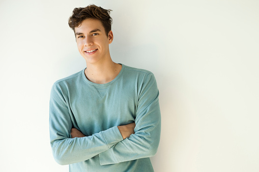 Portrait of a smiling young man arms crossed on a white background.