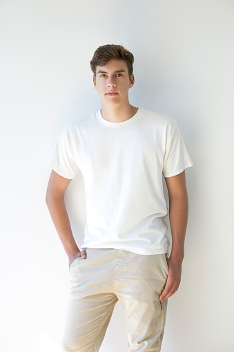 Portrait of a young man wearing a white t-shirt on a white background.