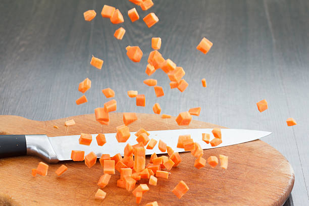 Carrot falls on the board for cutting. Vegetables in motion.