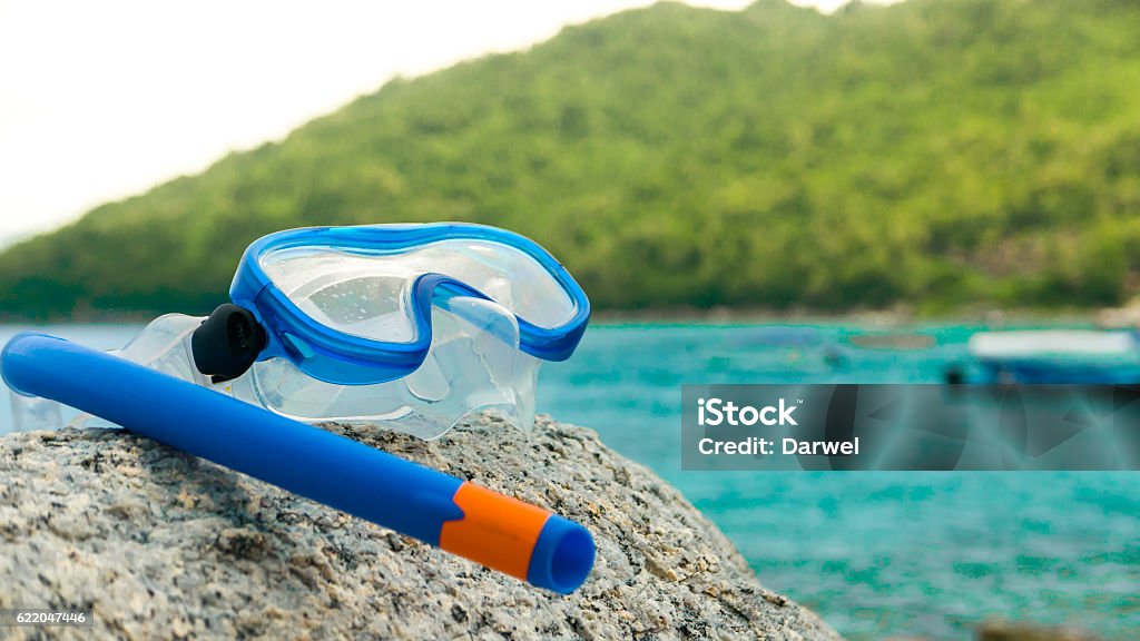 Snorkeling equipment: snorkel and diving google on the stone. Snorkeling equipment: snorkel and diving google on the stone. Tropical island, sea, beach and boats in background. Asia Stock Photo